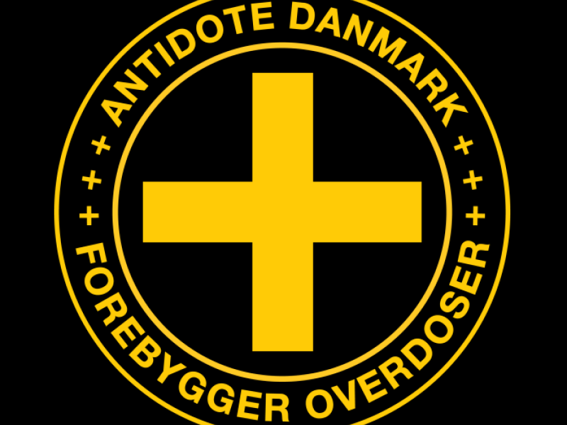 Antidote Danmarks logo - et gult kryds med to cirkler omkring